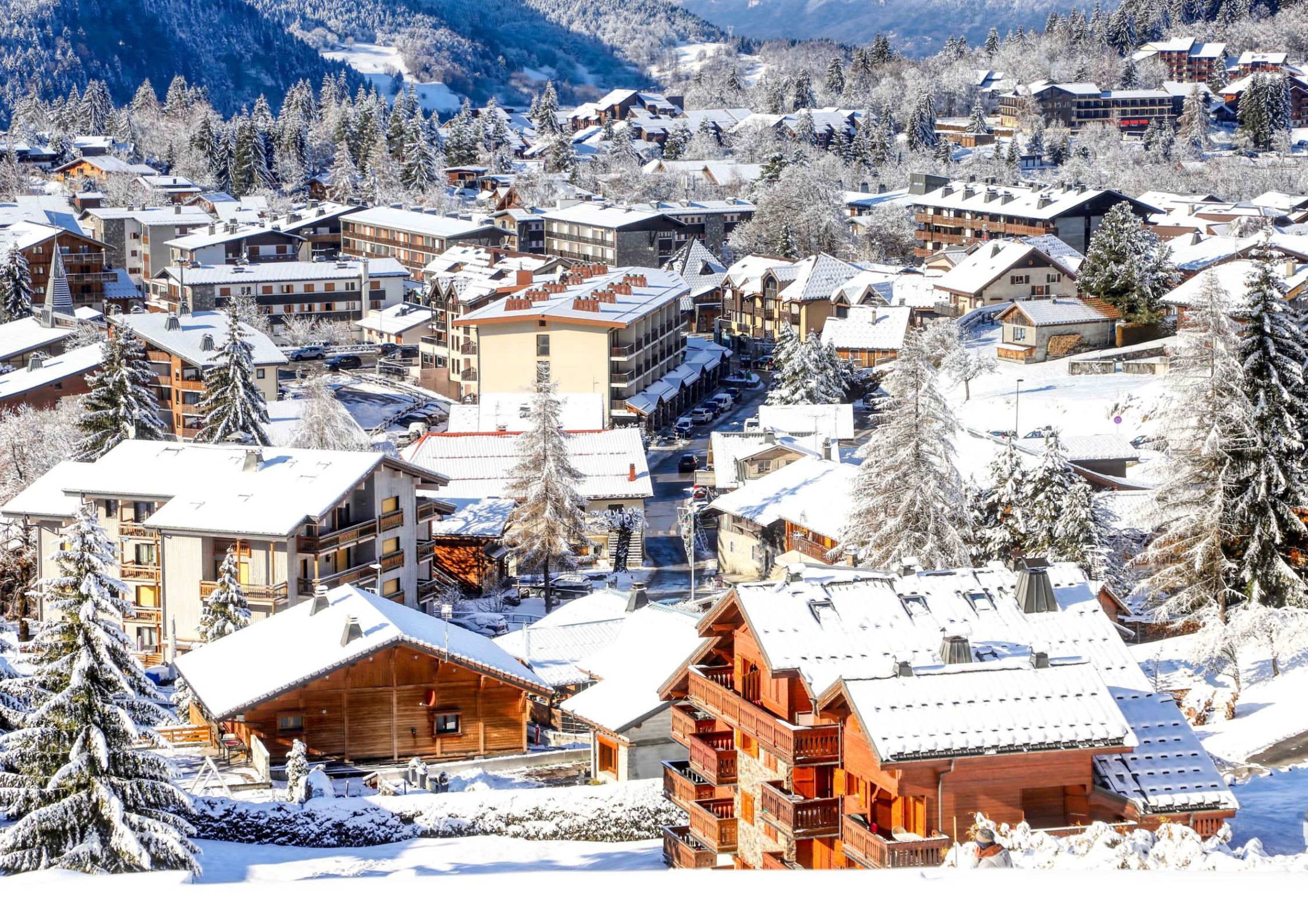 Les Carroz village from above in winter with traditional Savoyard chalets and snow-covered pine trees