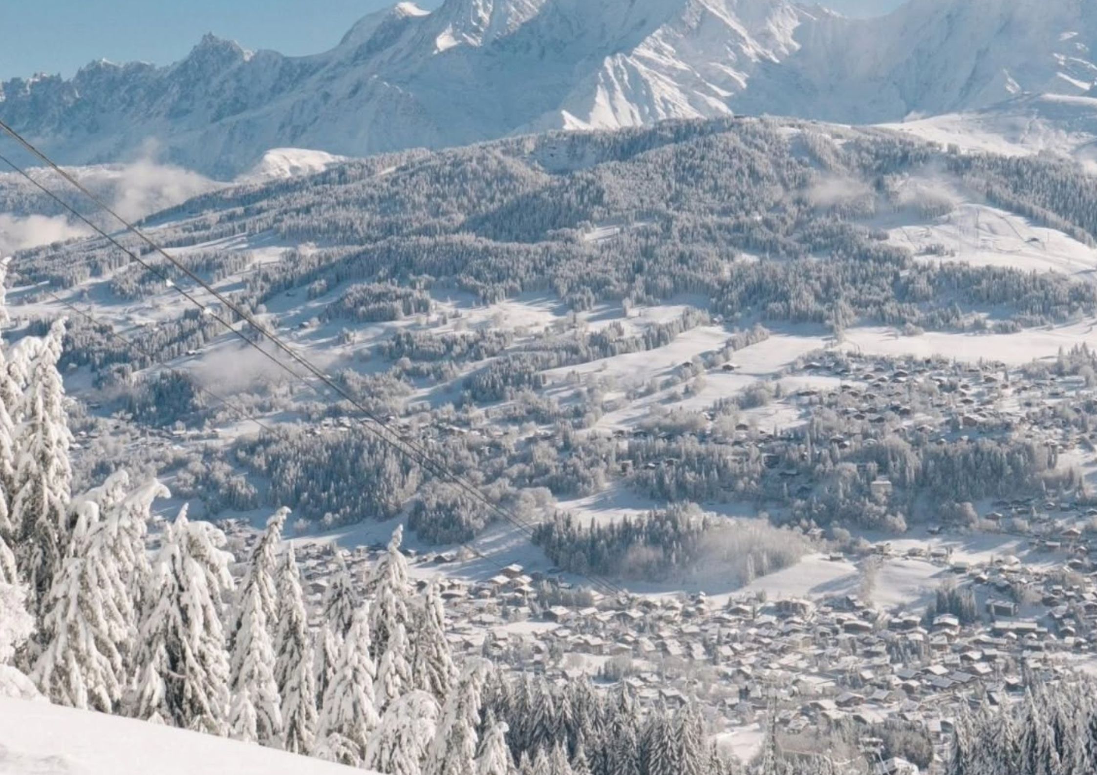 Manigod ski area from above with tree-lined pistes and Aravis mountain peaks in the background
