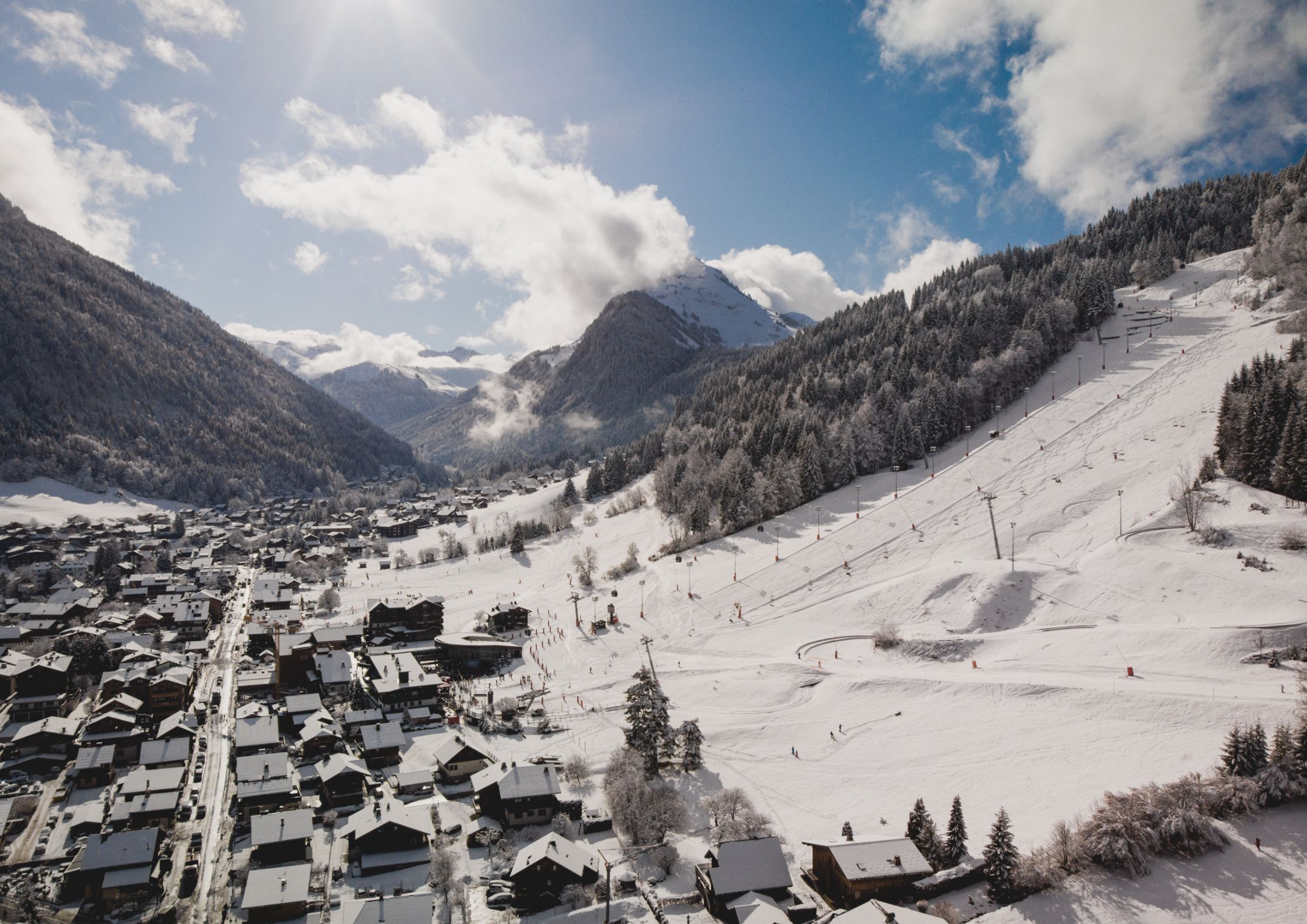Aerial view of snowy Morzine village and tree-lined ski slopes in the French Alps.